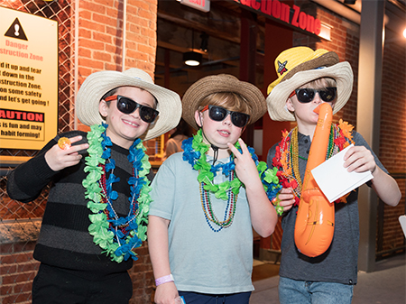 Three boys pose wearing cowboy hats and holding props at the Bash