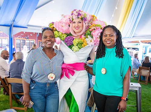 2025 gala attendees smile for a photo with a colorful human flower bouquet