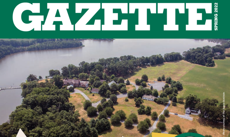 Aerial view of a riverside landscape with houses, trees, open fields, and water under a bright sky. Text at the top reads GAZETTE SPRING 2022..
