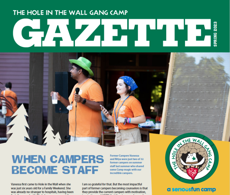 Two staff members in orange shirts speak and smile on stage at The Hole in the Wall Gang Camp. A badge with a raccoon in a hat is in the lower right. The headline reads, When Campers Become Staff..