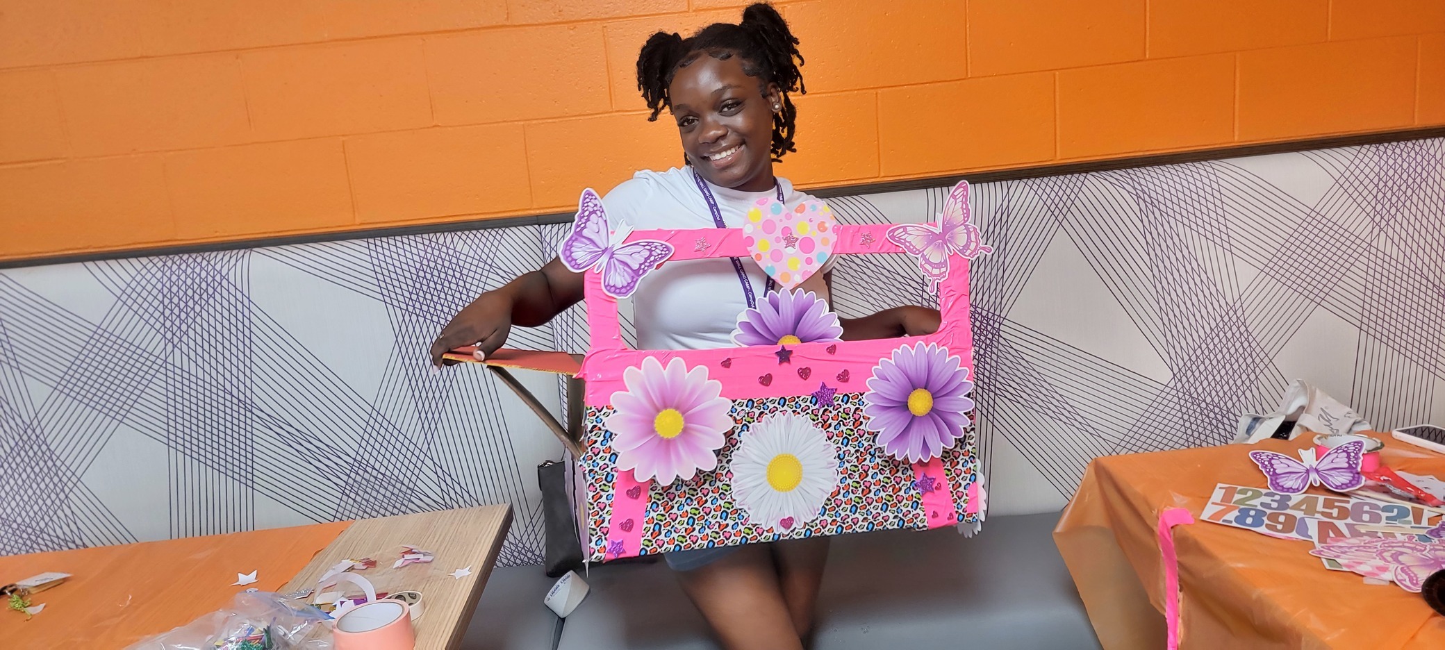 Camper child smiles in her pink flowers decorated cardboard car at a CampOut event